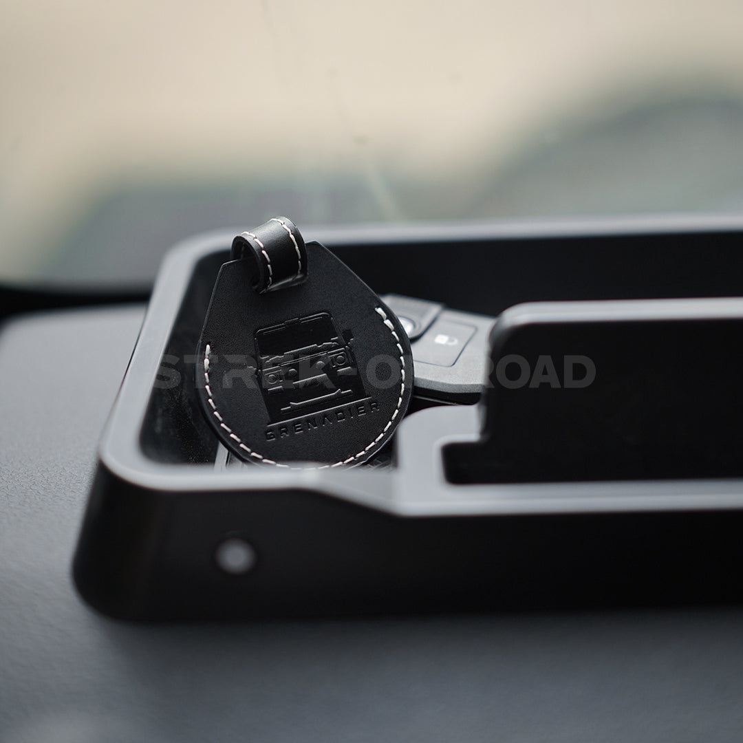 Black car keychain with a logo on a car dashboard