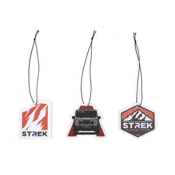 Three hanging air freshener cards for INEOS Grenadier: Grenadier Silhouette in Wild Bluebell scent, STREK Claw Logo in Oud Wood scent, and STREK Expedition Badge in Wood Sage & Sea Salt scent.