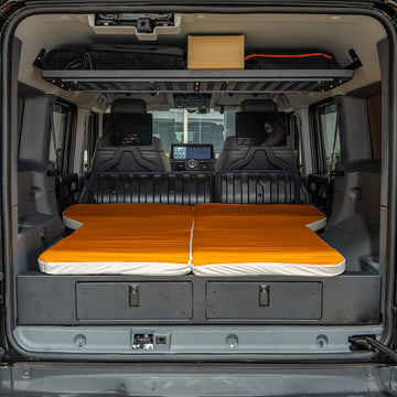 Straight-on rear trunk view of the orange sleeping mattress fitted flush on the INEOS Grenadier drawer system.