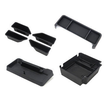 Complete collection of interior cabin storage organizers including dashboard tray, armrest box, door pockets, and behind-screen tray on a white background for INEOS Grenadier.