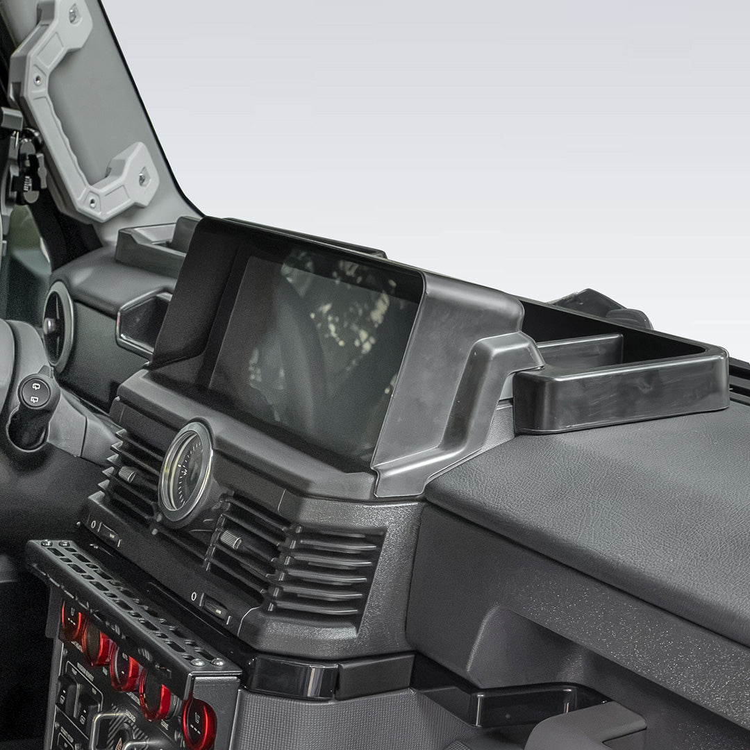 Front cabin interior of an INEOS Grenadier showing installed center console armrest organizer and dashboard storage compartments.