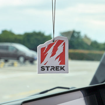 STREK Claw Logo Air Freshener Card in Oud Wood scent hanging inside an INEOS Grenadier interior.