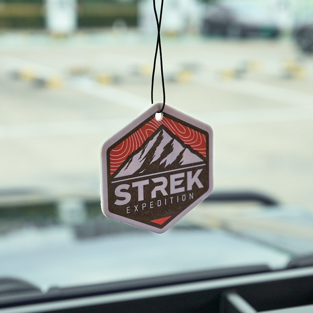 STREK Expedition Badge Air Freshener Card in Wood Sage & Sea Salt scent hanging inside an INEOS Grenadier interior.