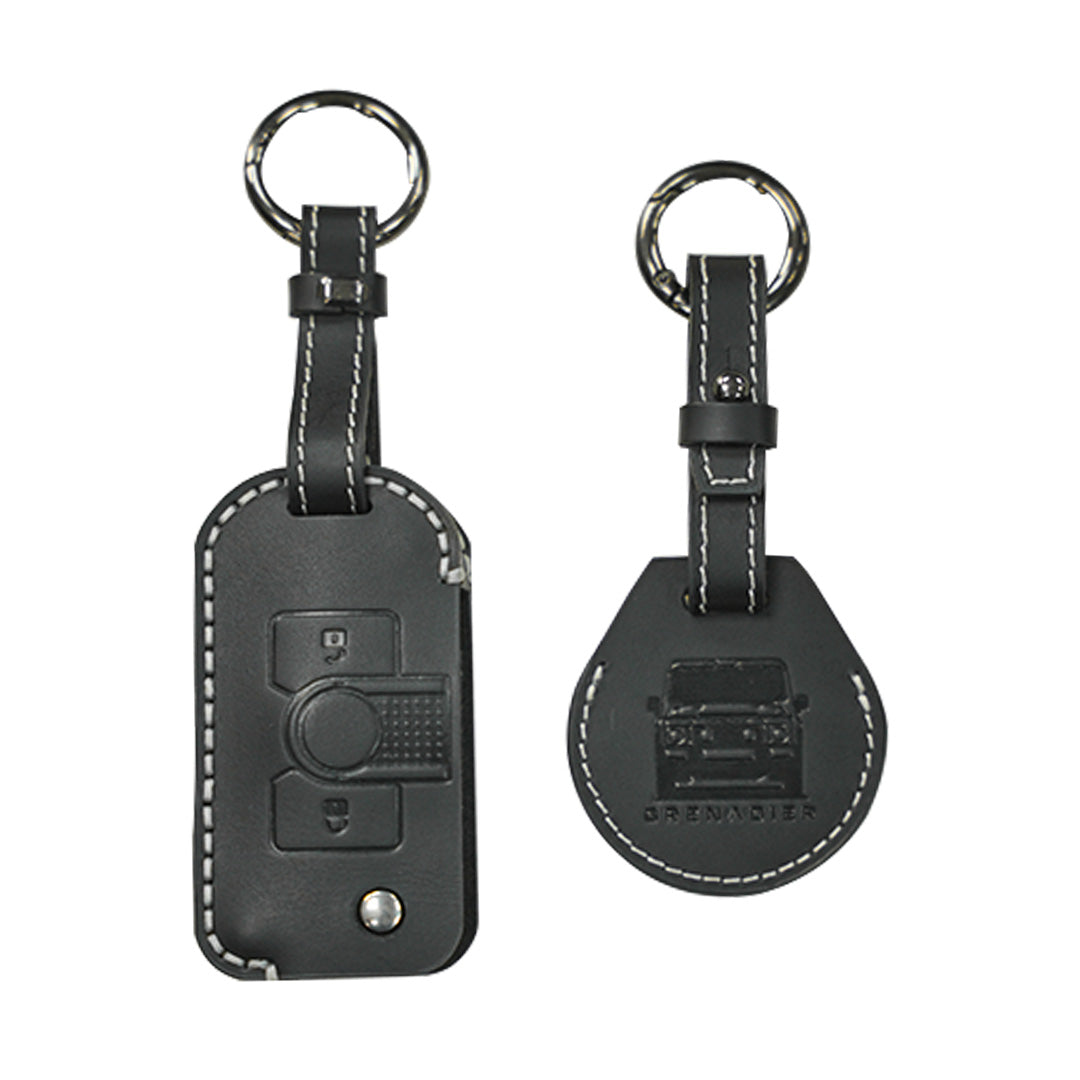 STREK Off Road black genuine leather keychain cover and matching AirTag case set compatible with INEOS Grenadier fob, featuring white contrast stitching on a white background.