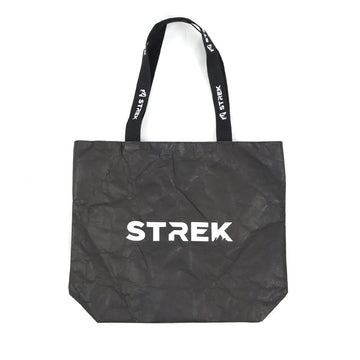 Full front product view of the STREK Overland Tyvek Utility Tote Bag with STREK logo on a black crinkle-textured tote body.
